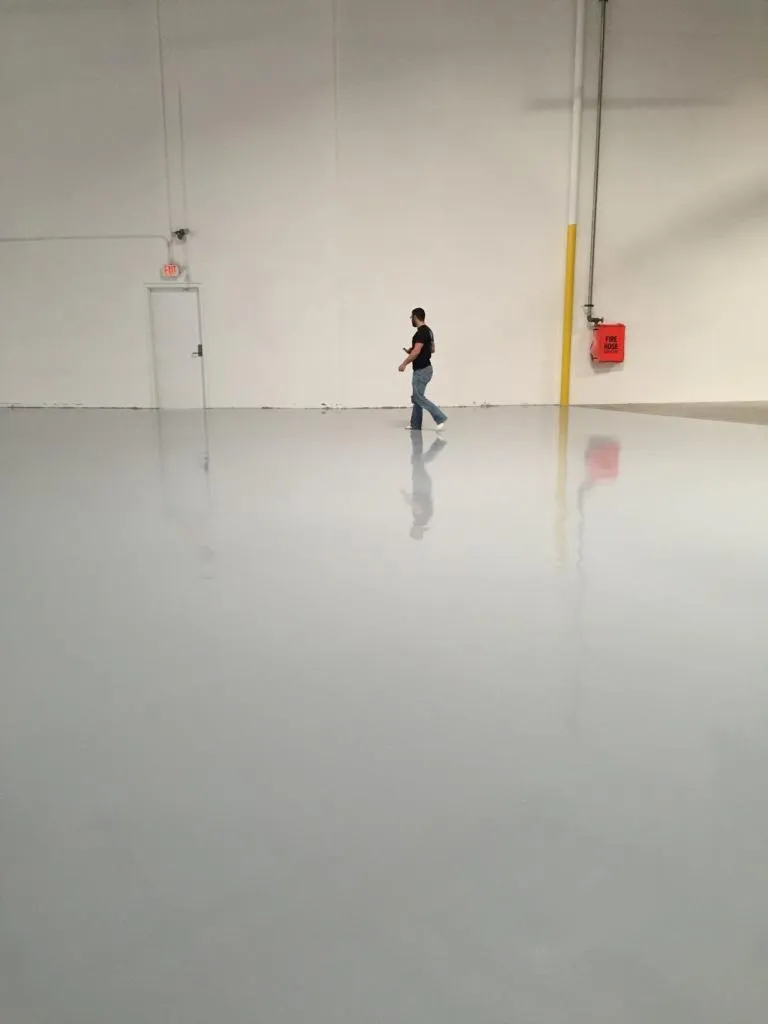 White epoxy warehouse floor with a worker walking across